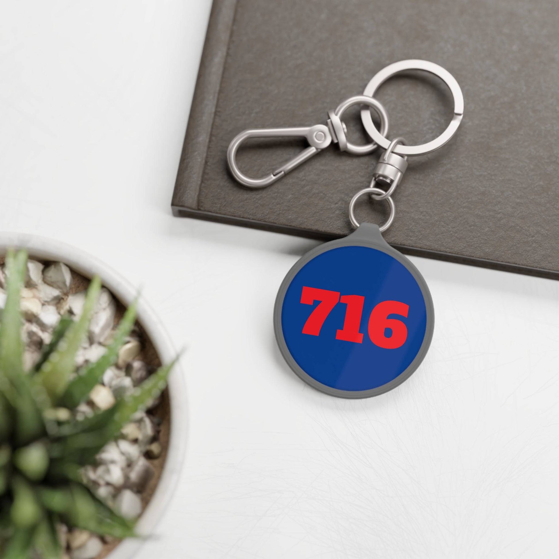 front of 716 blue metal keychain with red text on desk